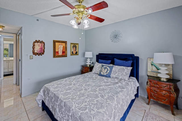 bedroom featuring ceiling fan, ensuite bathroom, light tile patterned floors, and a textured ceiling