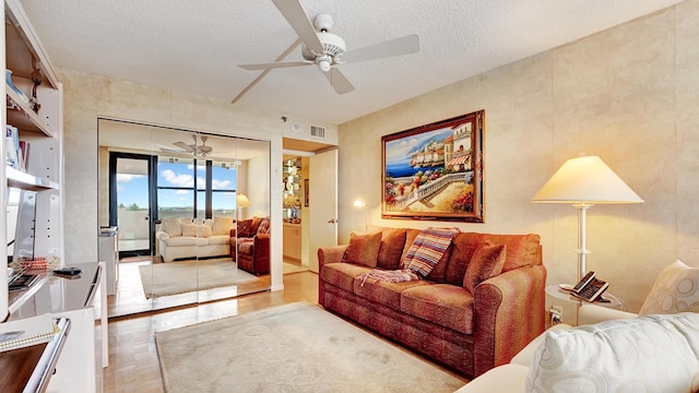 living room with ceiling fan, a textured ceiling, and light hardwood / wood-style flooring