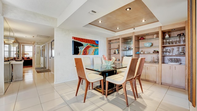 tiled dining space with a tray ceiling