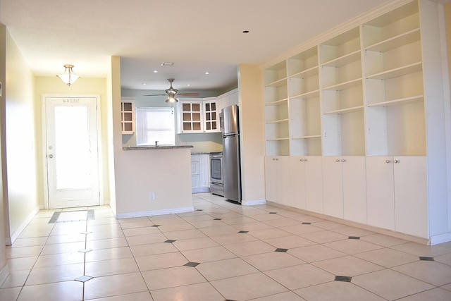 unfurnished living room featuring light tile patterned floors, ceiling fan, and built in shelves