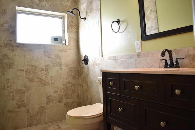 bathroom featuring tiled shower, vanity, toilet, and tile walls