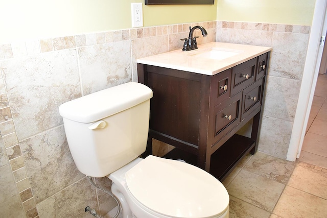 bathroom with vanity, toilet, and tile walls