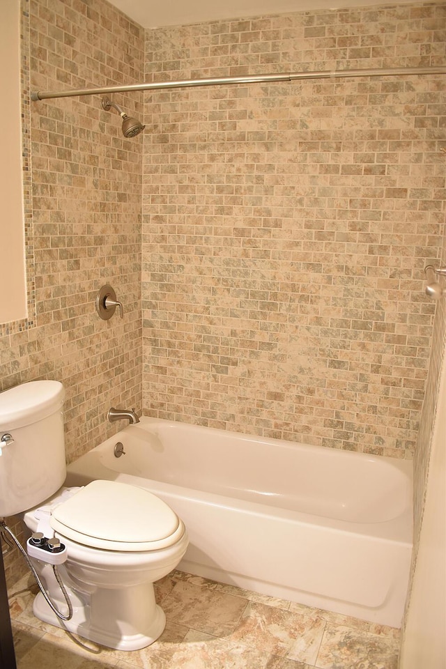 bathroom with toilet and tiled shower / bath