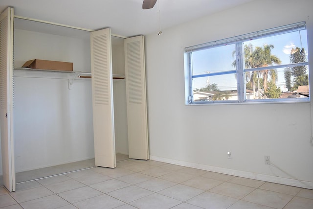 unfurnished bedroom featuring ceiling fan, multiple closets, and light tile patterned flooring