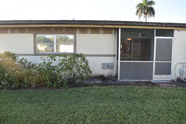 view of side of property featuring a yard, ceiling fan, and a sunroom