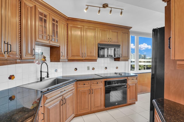 kitchen with black appliances, sink, decorative backsplash, dark stone countertops, and light tile patterned floors