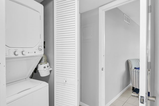 laundry area featuring light tile patterned floors and stacked washer and clothes dryer