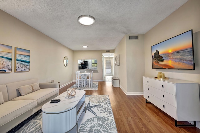 living room with a textured ceiling and light hardwood / wood-style flooring