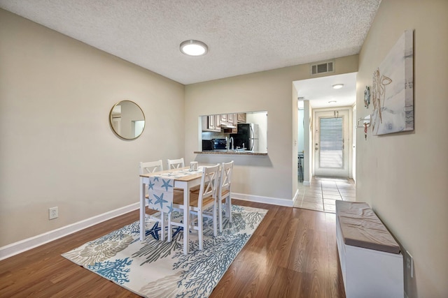 dining area with a textured ceiling and hardwood / wood-style flooring