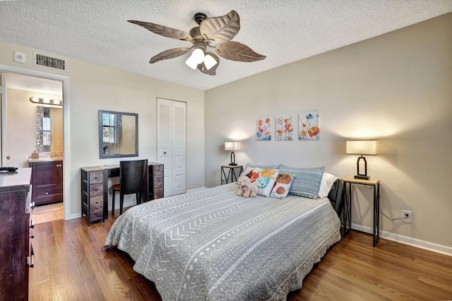 bedroom with a textured ceiling, a closet, hardwood / wood-style flooring, and ceiling fan