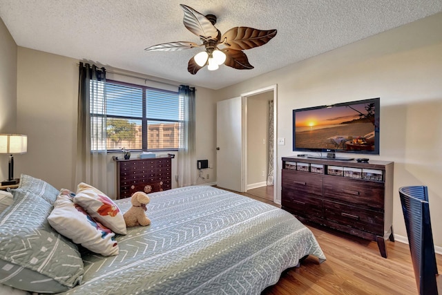 bedroom with ceiling fan, light wood-type flooring, and a textured ceiling