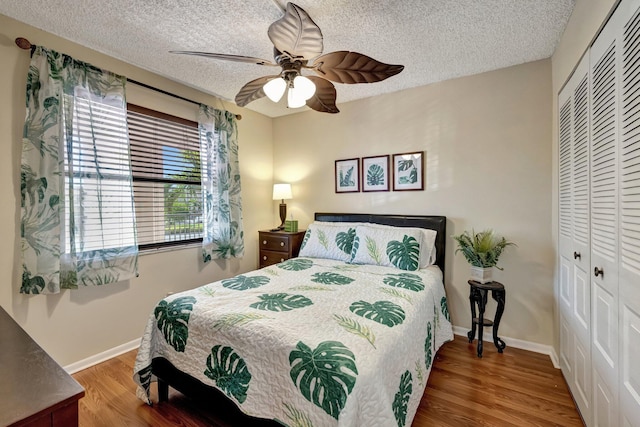 bedroom featuring ceiling fan, a closet, wood-type flooring, and a textured ceiling