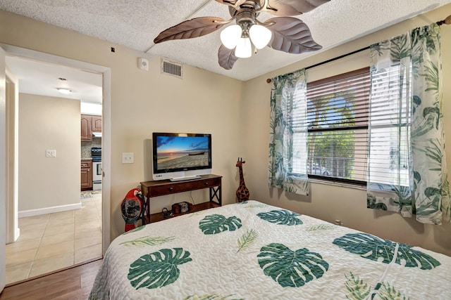 bedroom with hardwood / wood-style floors, ceiling fan, and a textured ceiling