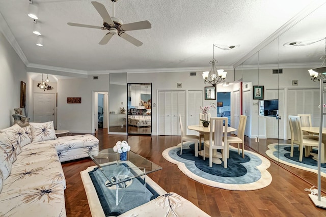 living room with ceiling fan with notable chandelier, dark hardwood / wood-style flooring, ornamental molding, and a textured ceiling