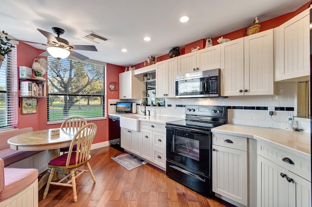 kitchen featuring white cabinets, sink, light hardwood / wood-style flooring, and black appliances