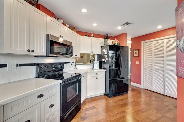 kitchen featuring white cabinets, backsplash, light hardwood / wood-style floors, and black appliances