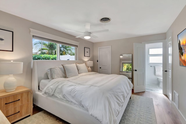 bedroom with ceiling fan, light hardwood / wood-style floors, connected bathroom, and multiple windows