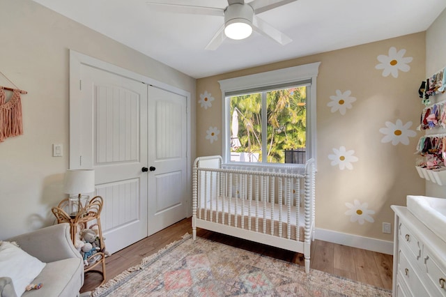 bedroom with a closet, ceiling fan, light hardwood / wood-style flooring, and a nursery area