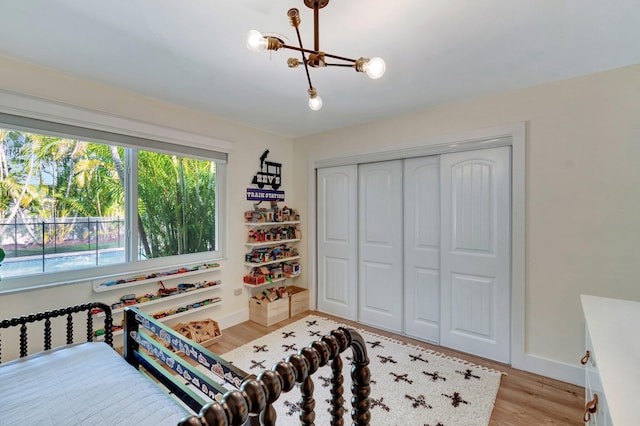 bedroom featuring a closet, light wood-type flooring, and an inviting chandelier