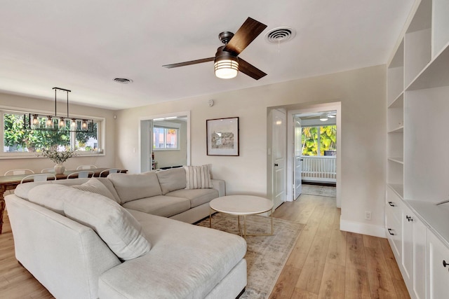 living room with plenty of natural light, ceiling fan, and light hardwood / wood-style flooring