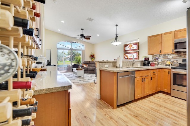 7708 Cherry Blossom Way, Boynton Beach, FL 33437 - kitchen with appliances with stainless steel finishes, a peninsula, open floor plan, light wood-type flooring, and backsplash