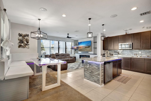 kitchen featuring light stone countertops, sink, stainless steel appliances, pendant lighting, and light tile patterned floors