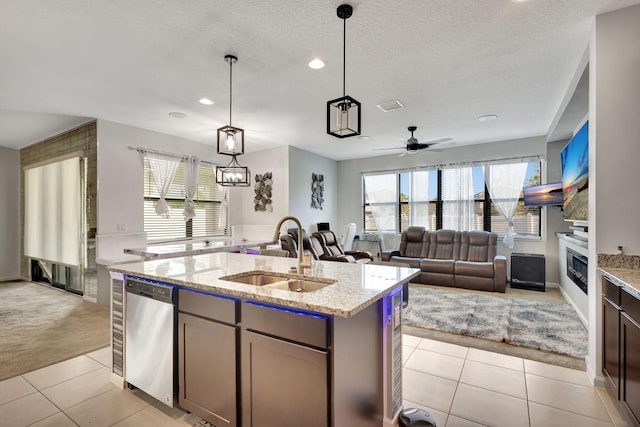 kitchen with light stone countertops, light carpet, stainless steel appliances, sink, and an island with sink