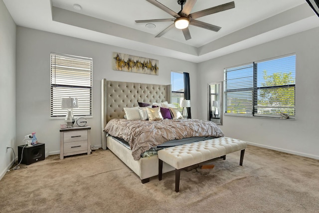 carpeted bedroom featuring a raised ceiling and ceiling fan