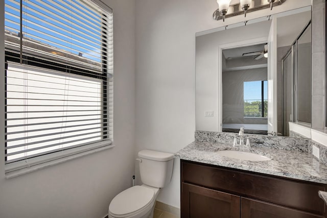 bathroom featuring ceiling fan, a shower with door, vanity, and toilet