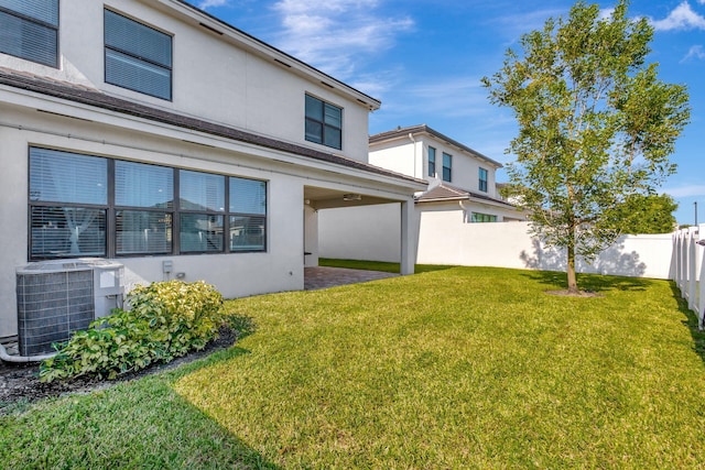 rear view of property featuring cooling unit and a lawn