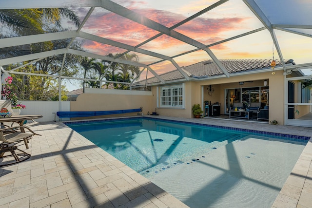 pool at dusk with a patio and glass enclosure