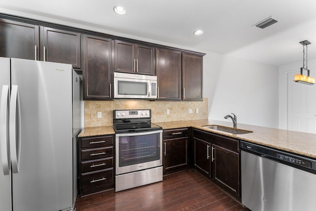 kitchen featuring sink, appliances with stainless steel finishes, hanging light fixtures, dark hardwood / wood-style floors, and kitchen peninsula