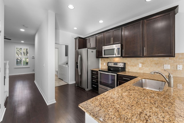 kitchen featuring sink, stainless steel appliances, light stone countertops, washer and dryer, and decorative backsplash