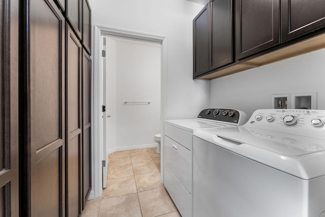 washroom featuring cabinets, light tile patterned flooring, and washer and clothes dryer