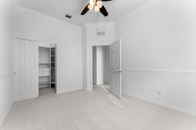 unfurnished bedroom with ceiling fan, light colored carpet, ornamental molding, and a closet