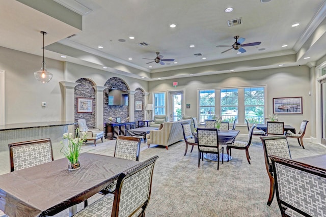 carpeted dining area with a raised ceiling, crown molding, and a healthy amount of sunlight