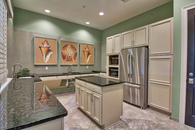 kitchen featuring stainless steel appliances, sink, decorative backsplash, and dark stone counters