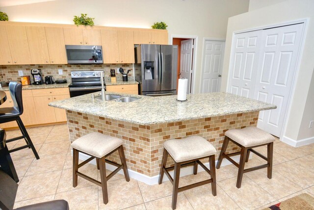 kitchen featuring sink, light brown cabinets, decorative light fixtures, stainless steel fridge with ice dispenser, and black range with electric stovetop