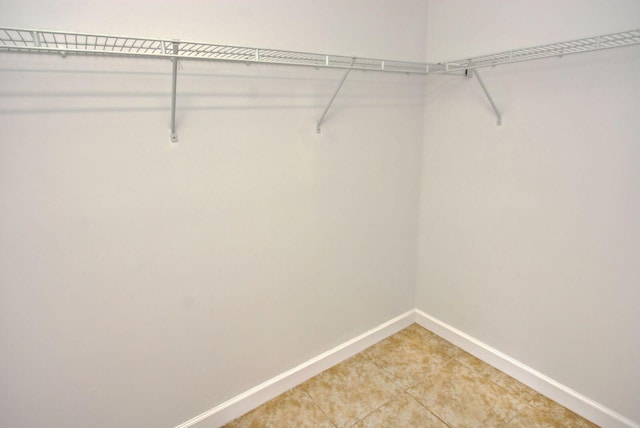 walk in closet with light tile patterned floors