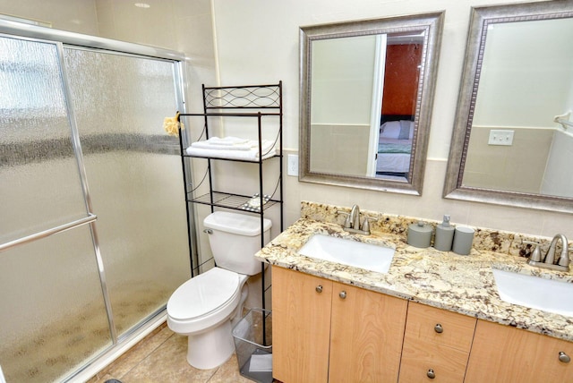 bathroom with double vanity, a shower stall, toilet, and a sink