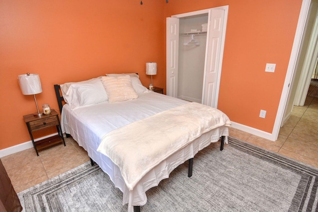 bedroom featuring light tile patterned flooring, baseboards, and a closet