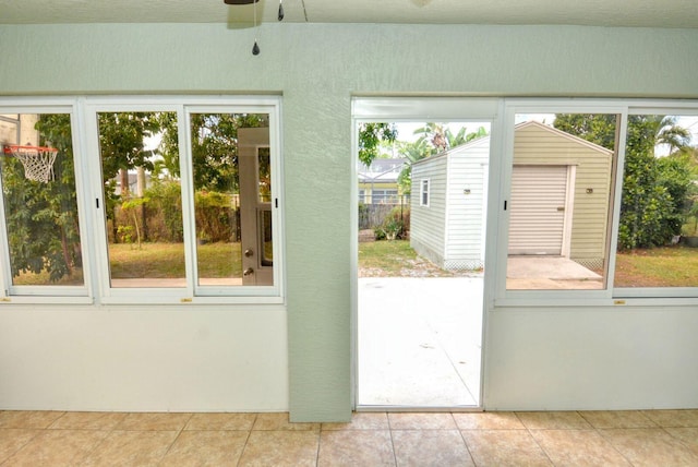 doorway to outside featuring tile patterned flooring, a ceiling fan, and a sunroom