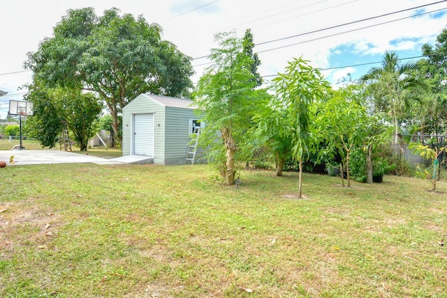 view of yard featuring a garage, an outdoor structure, a shed, and fence