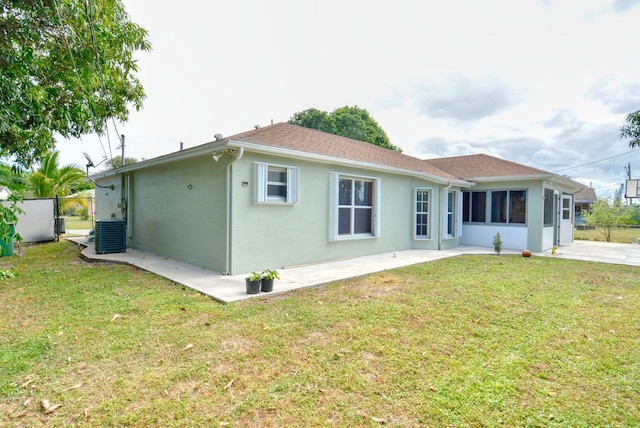 back of house with central air condition unit, a lawn, fence, and stucco siding