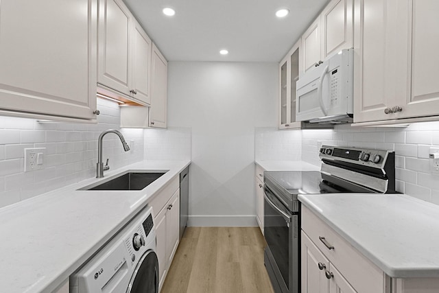 kitchen with sink, stainless steel appliances, light hardwood / wood-style flooring, washer / dryer, and white cabinets