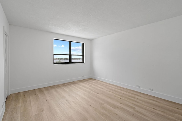 unfurnished room with light hardwood / wood-style floors and a textured ceiling