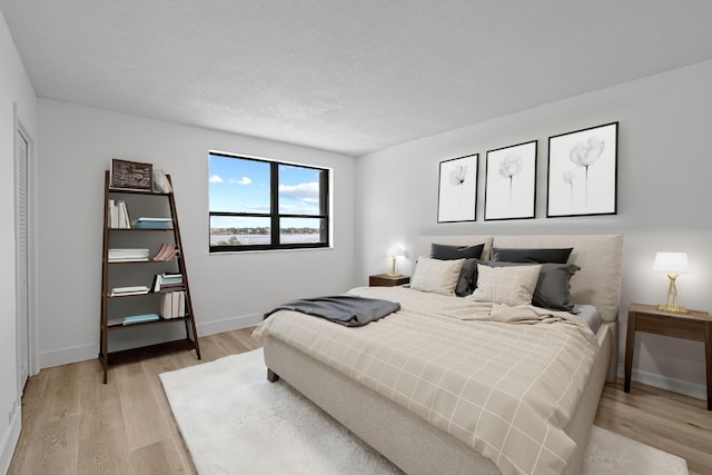 bedroom with a textured ceiling and light hardwood / wood-style flooring