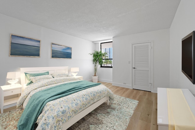 bedroom with light hardwood / wood-style floors and a textured ceiling