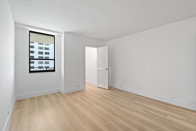 unfurnished room featuring a textured ceiling and light hardwood / wood-style floors