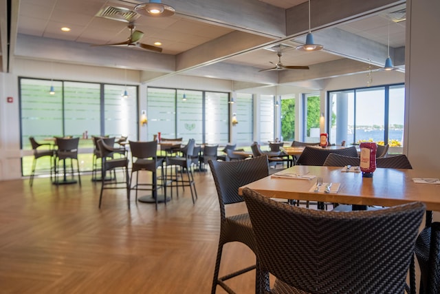 dining area featuring beam ceiling, light parquet floors, and ceiling fan